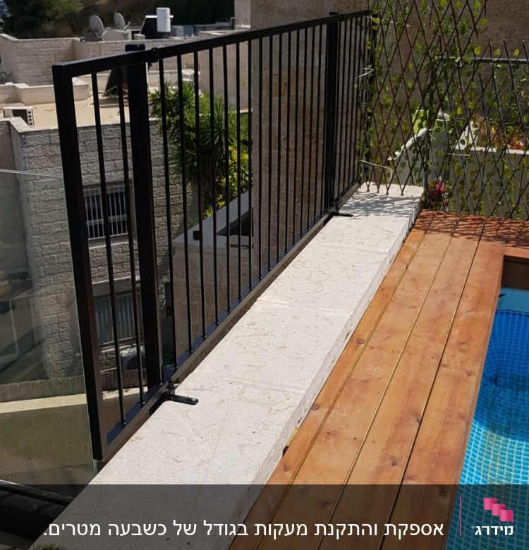 גדר מתכת שחורה ליד בריכה ודק עץ